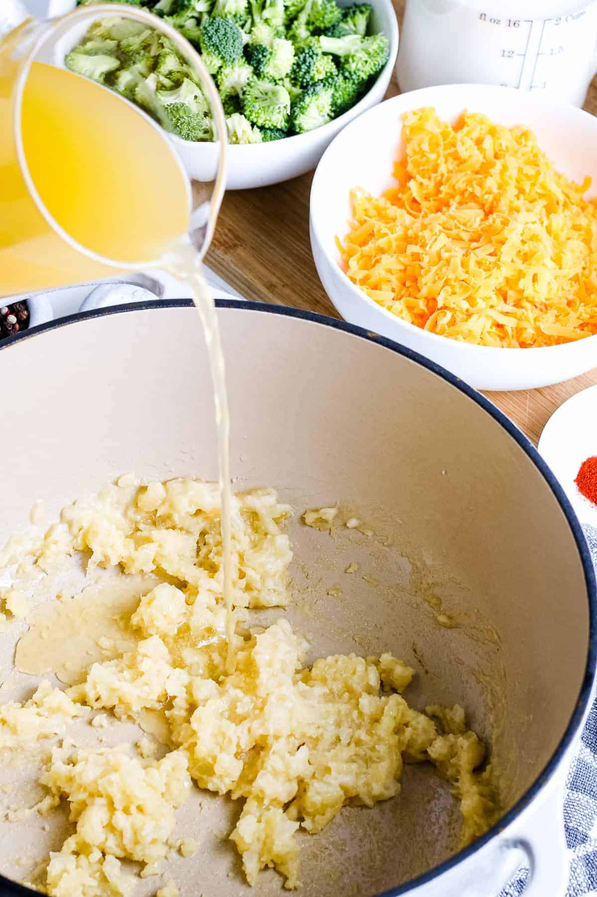 Pouring chicken broth into a roux of flour and butter in dutch oven.