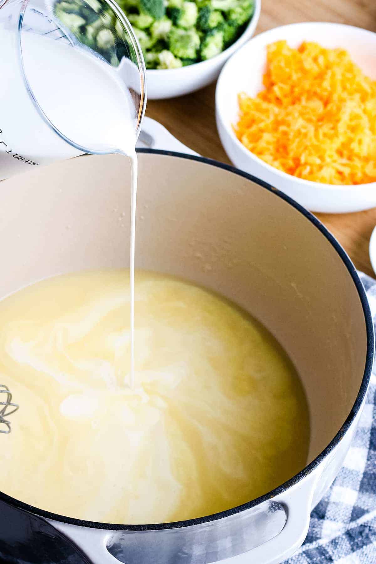 Pouring chicken broth into broccoli cheese soup base