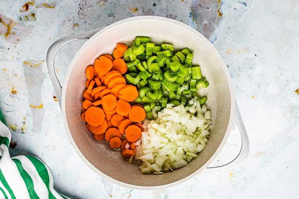 Dutch oven with diced carrots, celery and onion on the bottom.