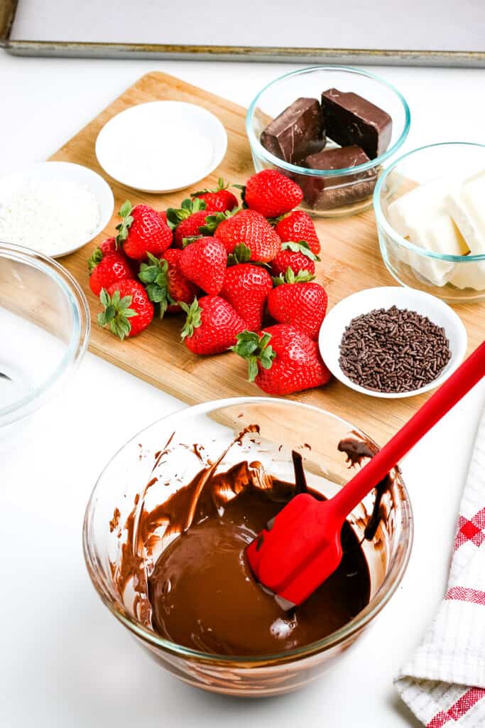 A glass bowl of melted chocolate with red spatula sitting in it