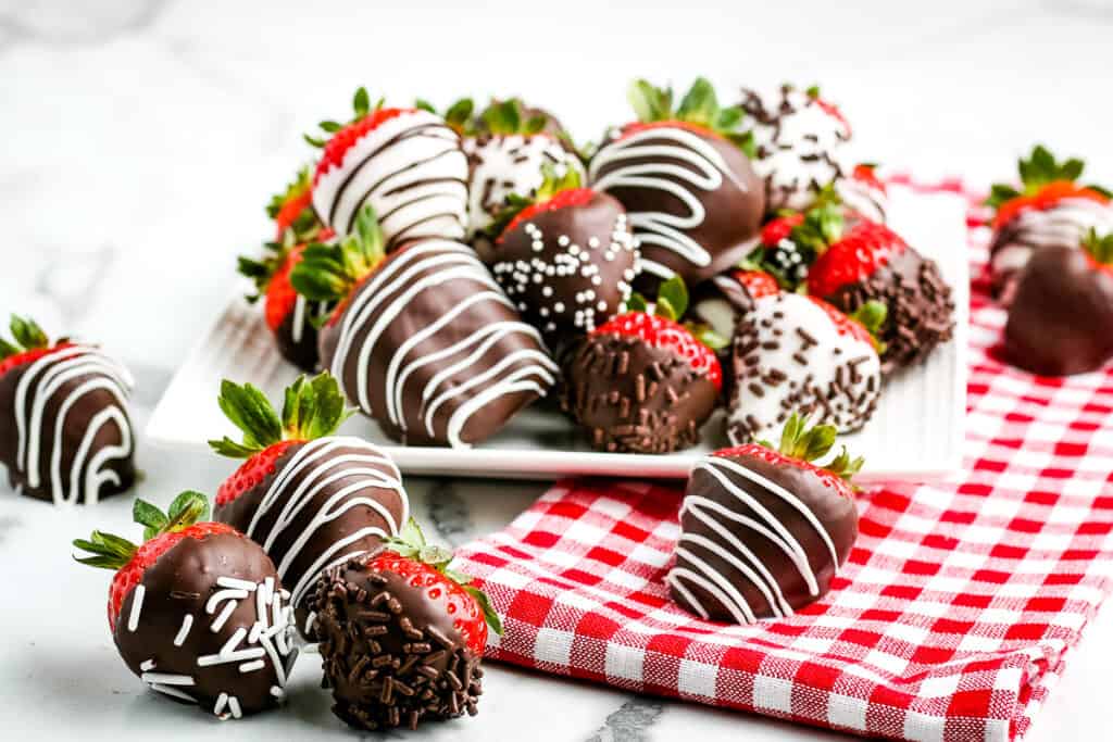 Chocolate covered strawberries on a plate with red and white checkered napkin