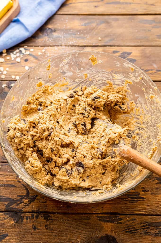 Glass bowl with oatmeal raisin cookie dough mixed up in it.