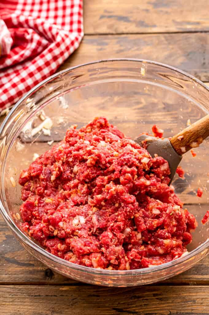 Mixed ingredients to make Italian meatloaf in glass bowl