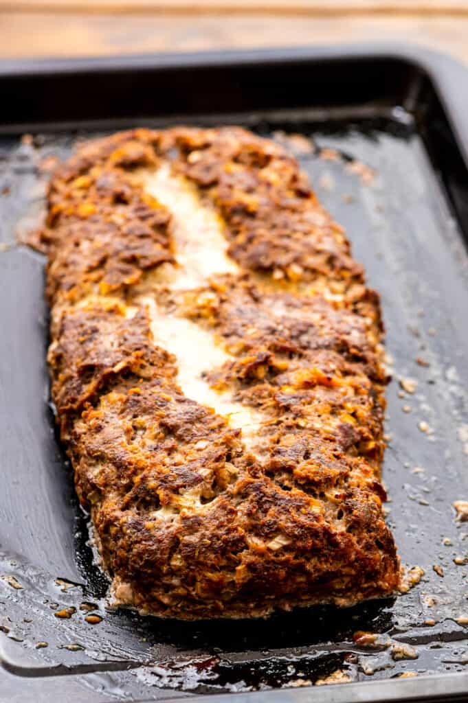 Baked cheese stuffed Italian meatloaf on pan.