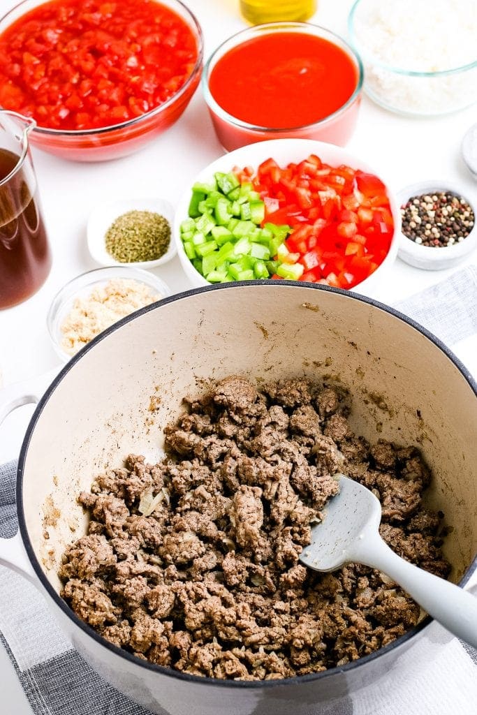 Dutch oven with browned ground beef in it.