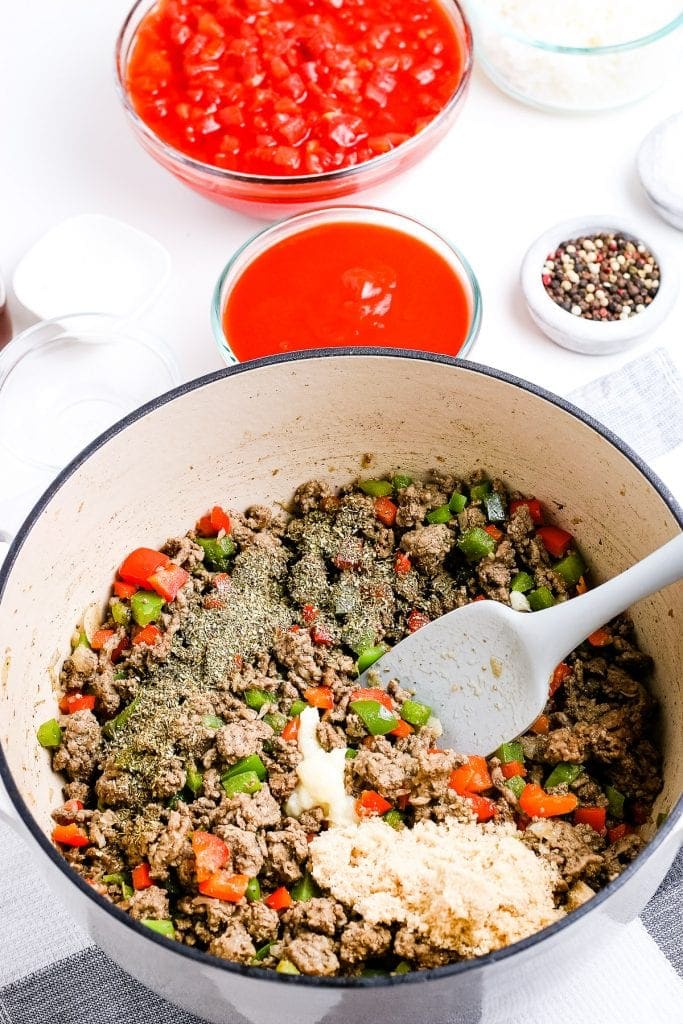 Dutch oven with a mixture of browned ground beef, peppers and seasonings.