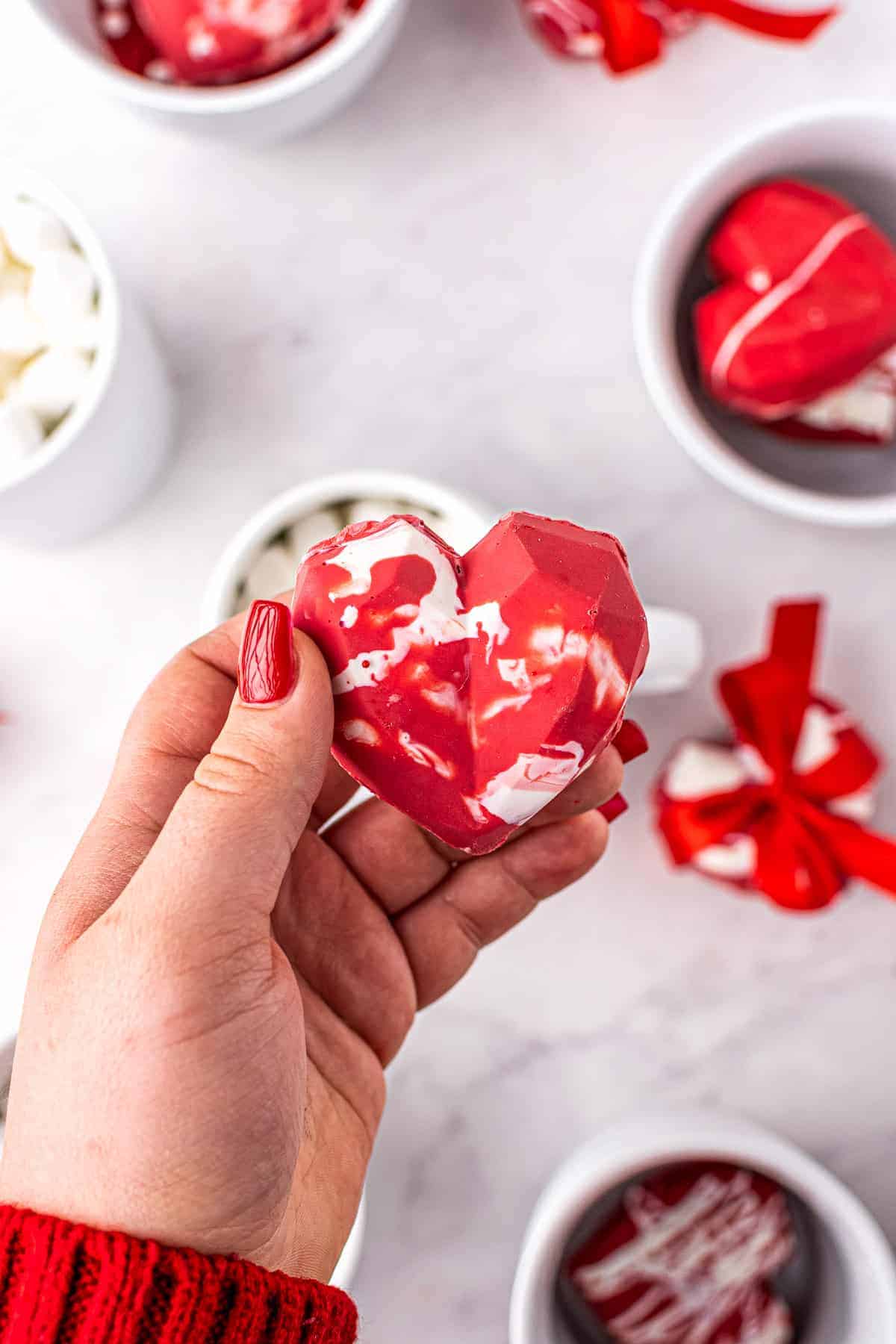 Hand holding heart hot cocoa bomb