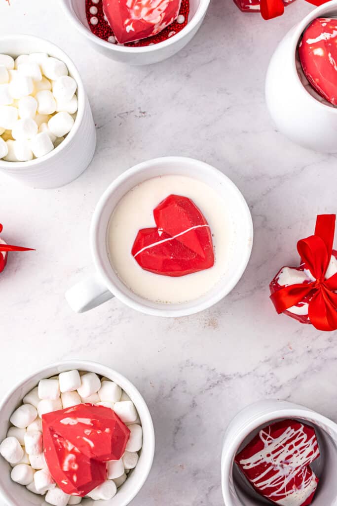 White mug with milk and heart shaped hot chocolate bomb