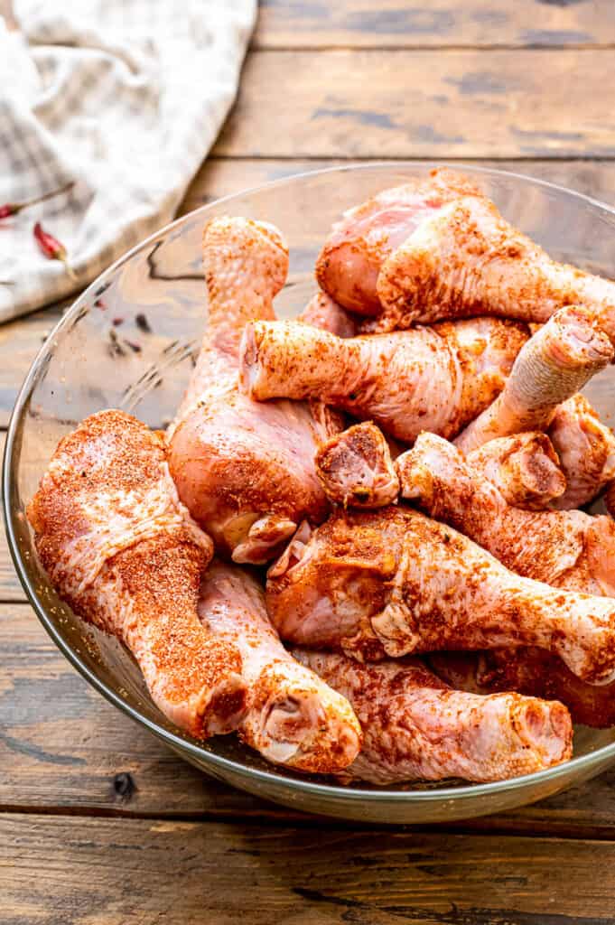 Glass bowl with chicken legs tossed in rub