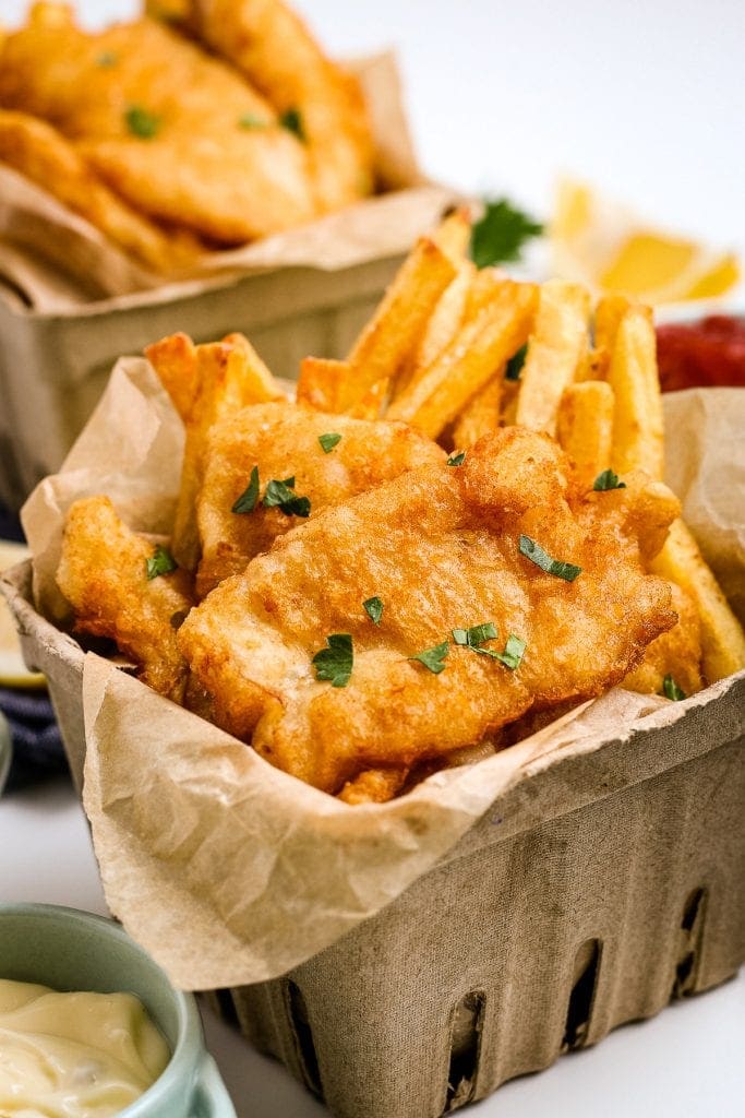 Beer Battered Fish and Chips in cardboard containers and garnished with parsley.