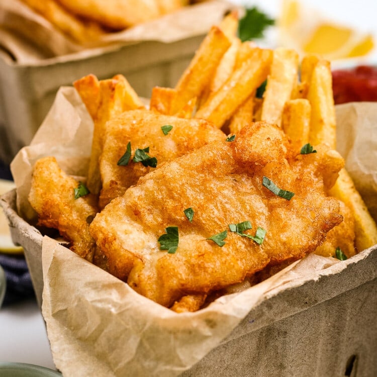 Beer Battered Fish and Chips in cardboard containers and garnished with parsley.