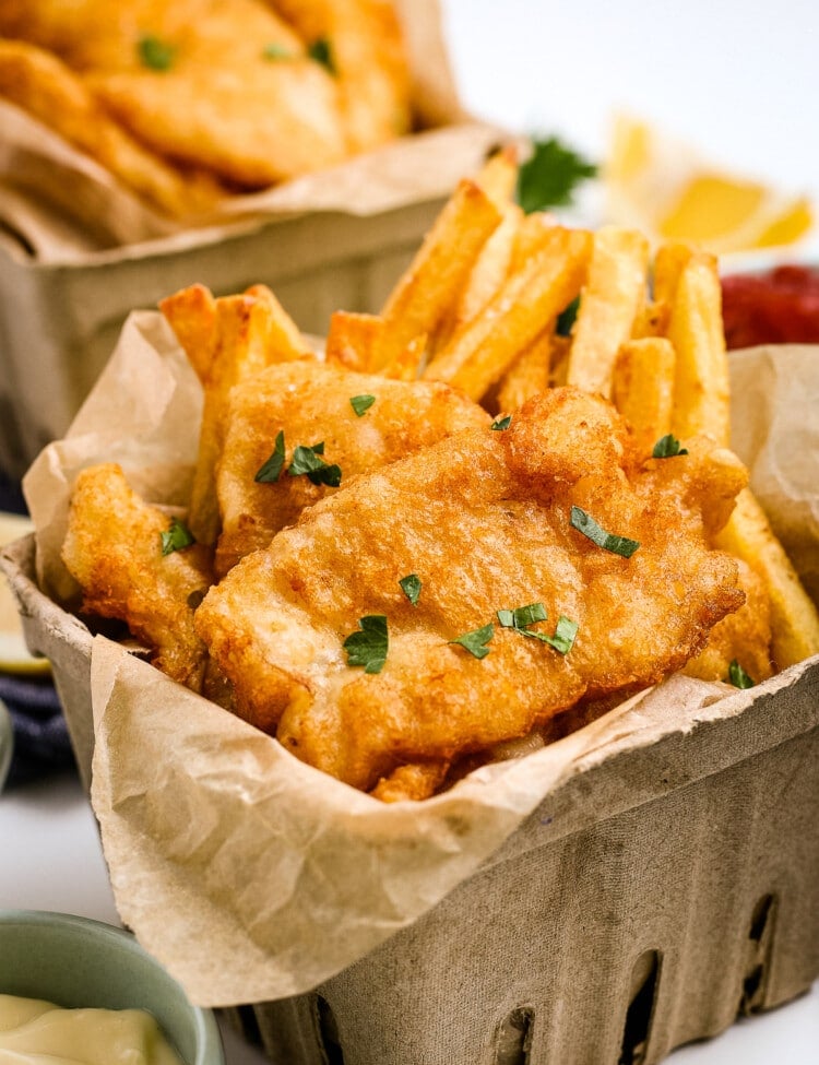 Beer Battered Fish and Chips in cardboard containers and garnished with parsley.