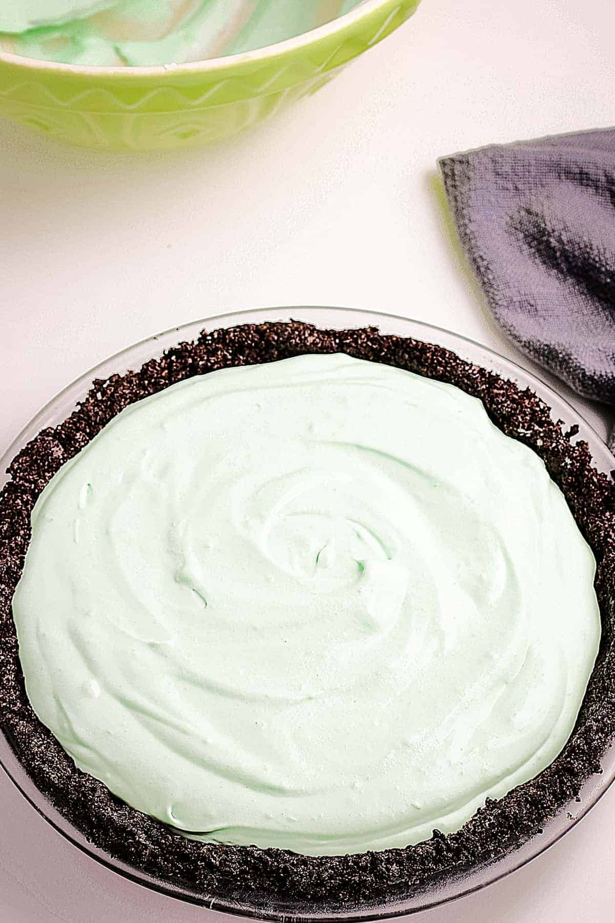 A pie dish with an Oreo pie crust filled with mint filling