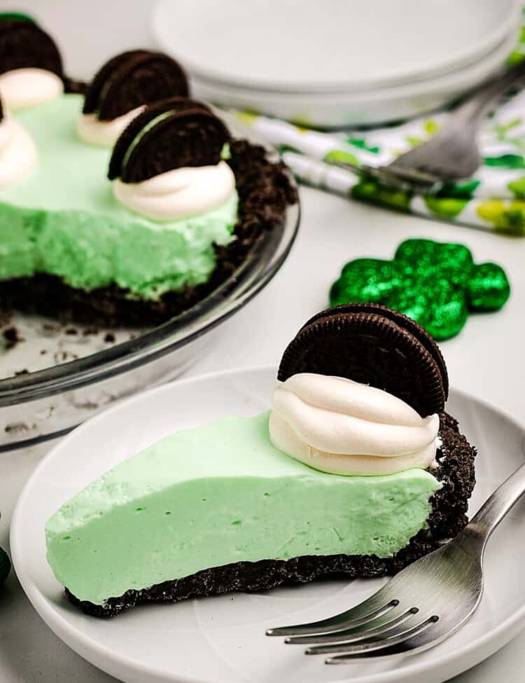 A slice of Grasshopper Pie on a white plate with fork next to it