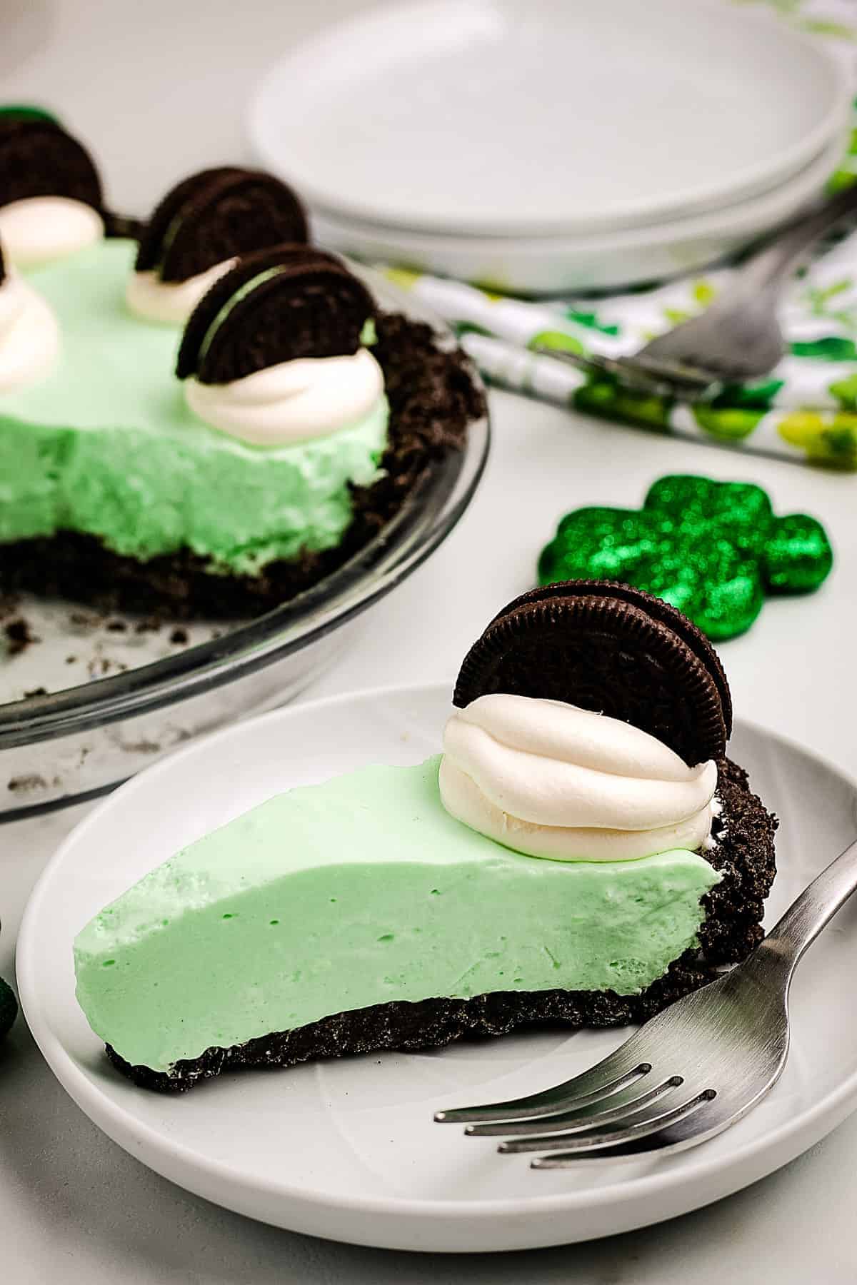 A slice of Grasshopper Pie on a white plate with fork next to it