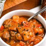 Overhead close up of a white bowl with Irish Beef Stew garnished with chopped parsley