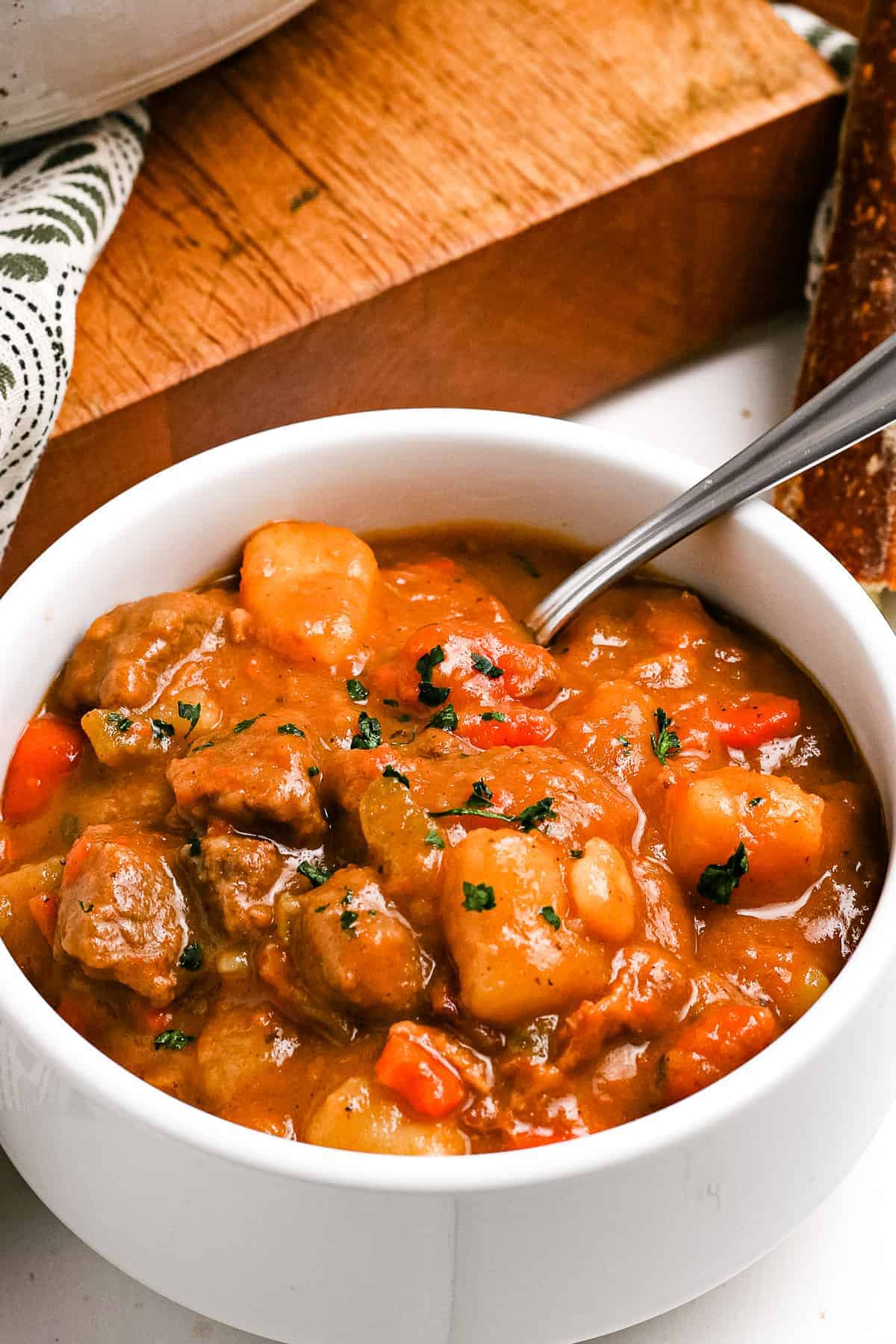 Overhead close up of a white bowl with Irish Beef Stew garnished with chopped parsley