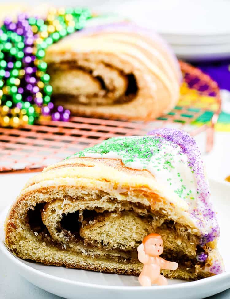 Slice of King Cake on a white plate with plastic baby