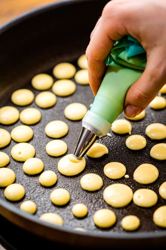 Squeeze mini pancakes into a skillet with piping bag