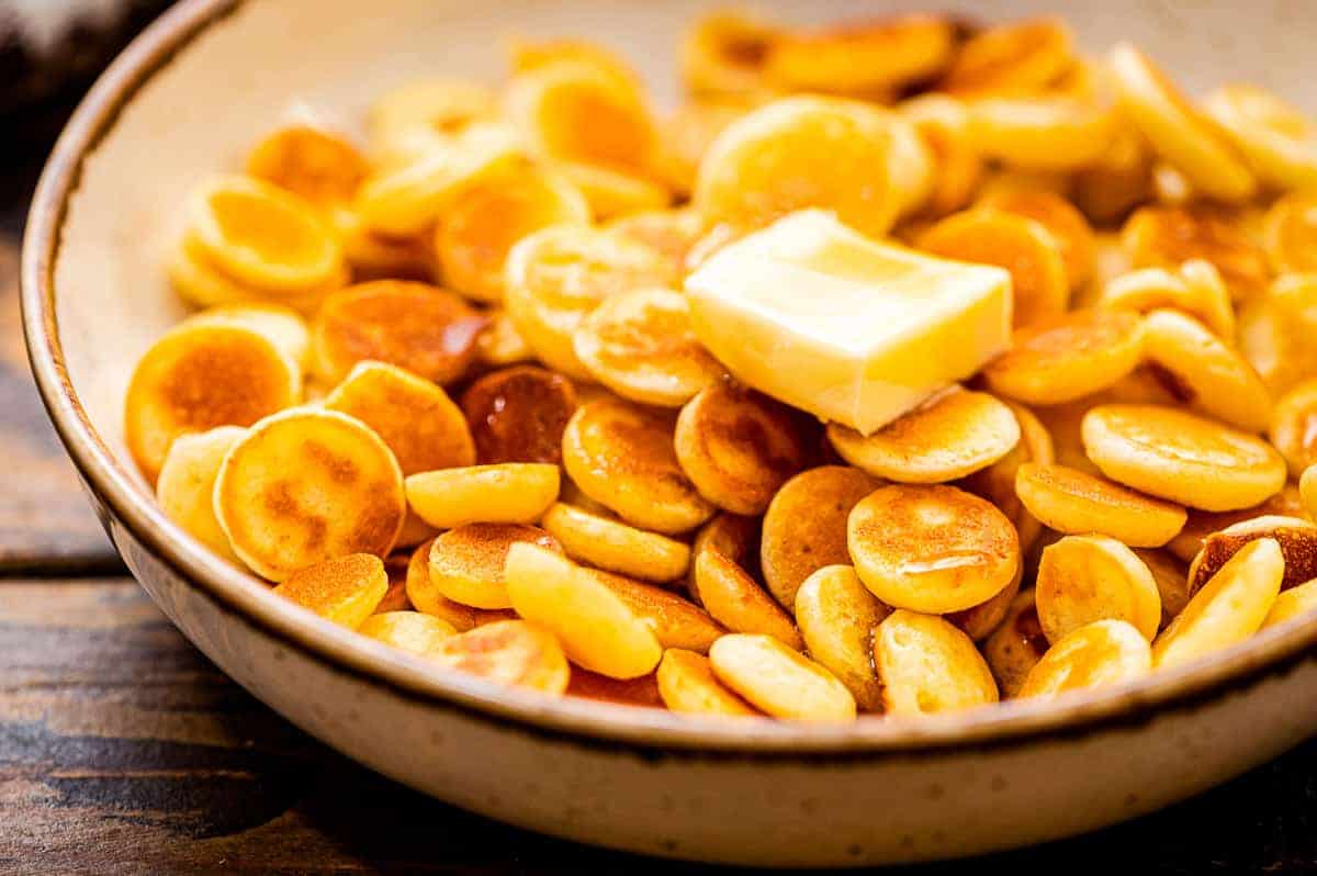 Bowl of mini pancake cereal with a slab of butter on top