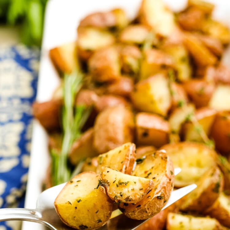 Oven Roasted Potatoes on a serving spoon with a platter of more potatoes in background