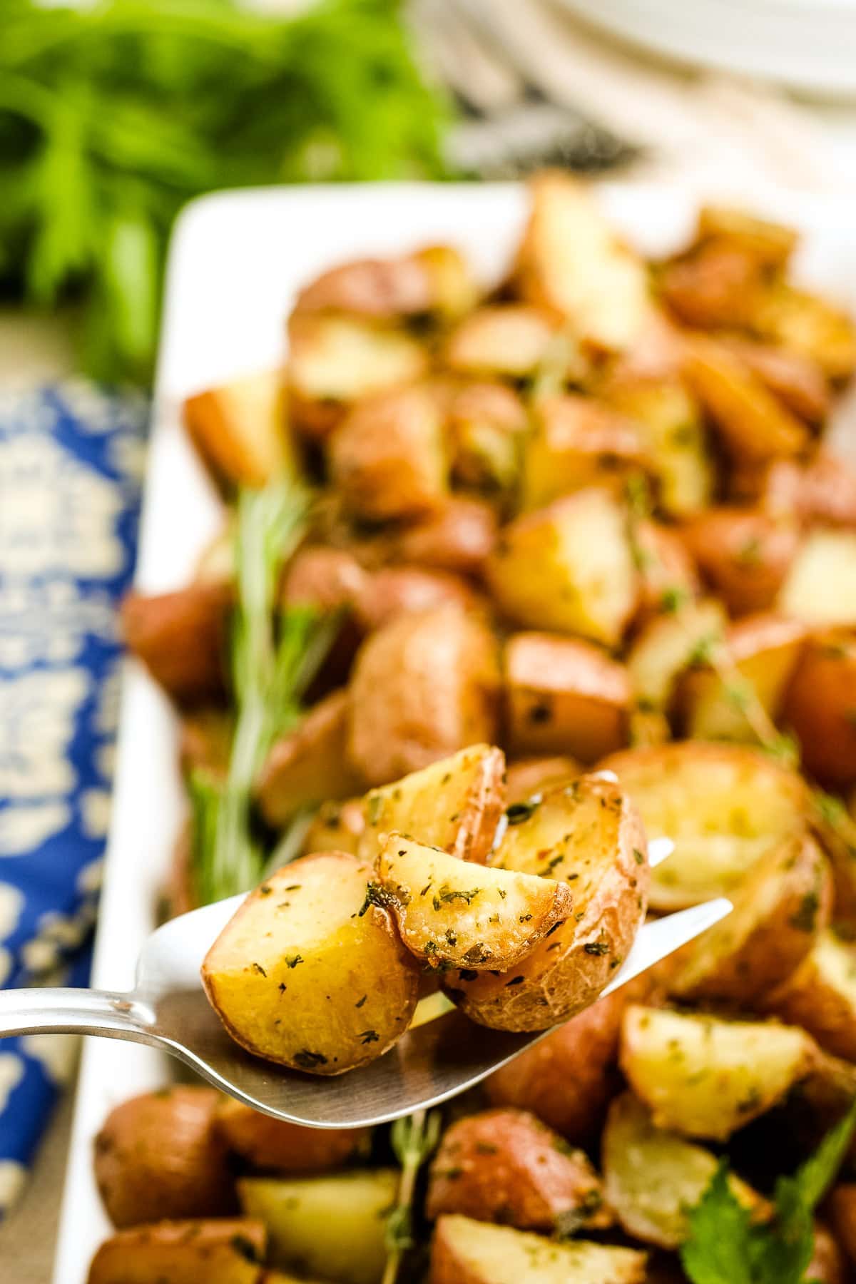 Oven Roasted Potatoes on a serving spoon with a platter of more potatoes in background