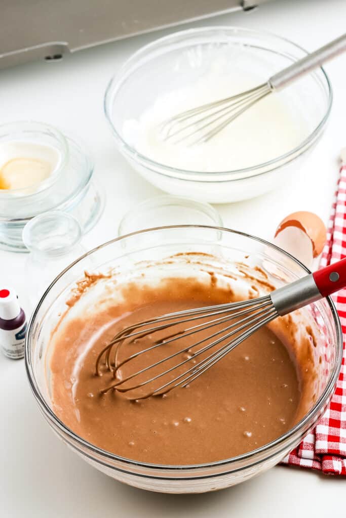 Glass bowl with batter for red velvet pancakes with whisk in it