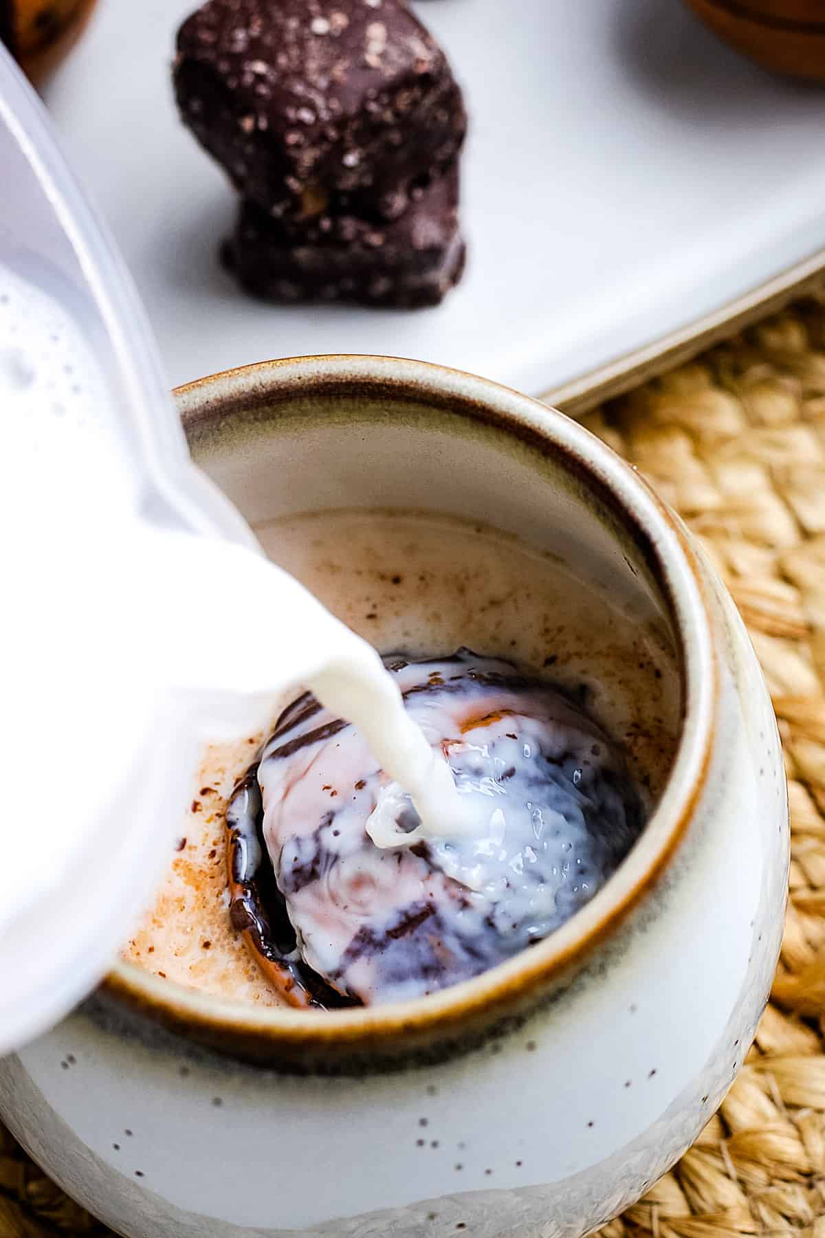 Hot milk being poured into a mug with salted caramel hot cocoa bomb