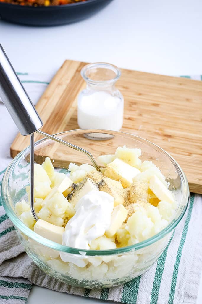 A glass bowl with ingredients to make mashed potatoes