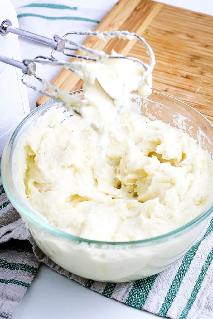 Glass bowl with hand mixer making mashed potatoes