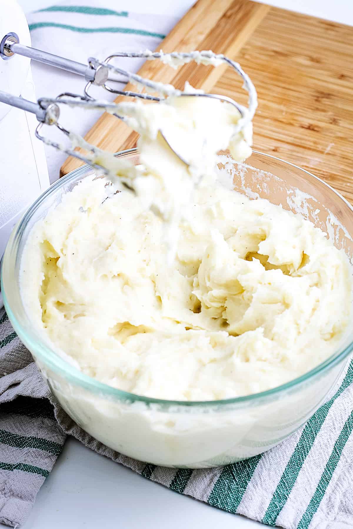 Glass bowl with hand mixer making mashed potatoes
