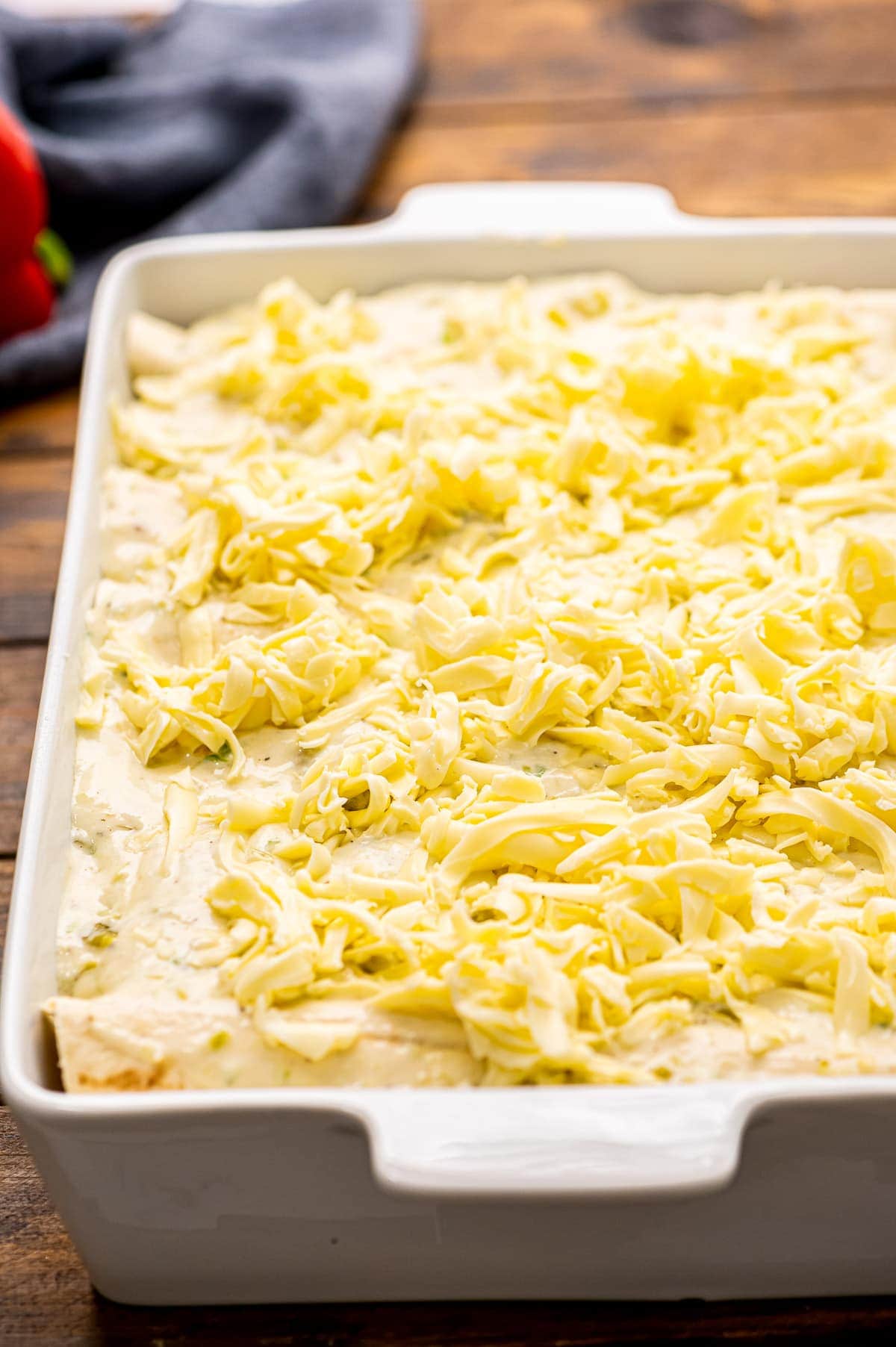 White casserole dish with shrimp enchiladas in it before baking.