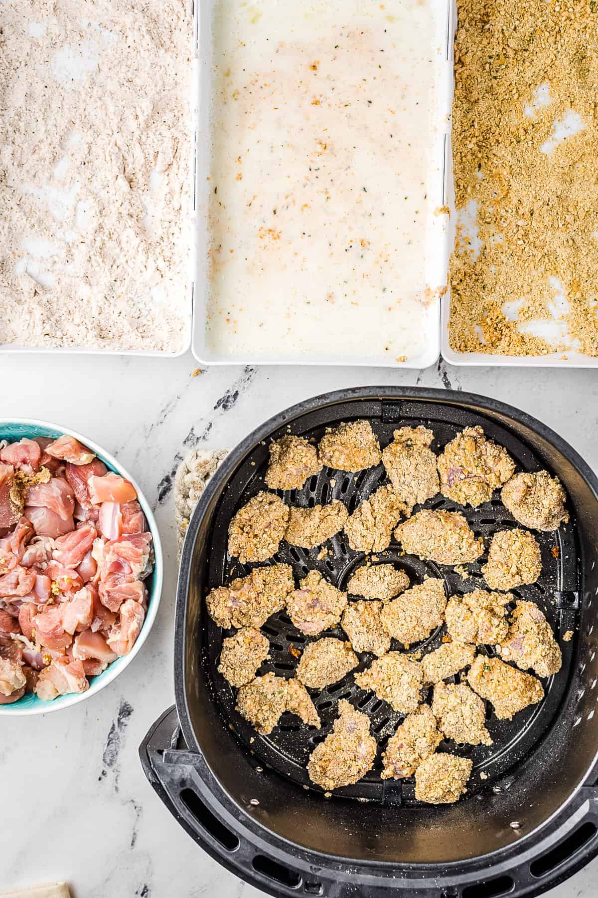 Raw breaded homemade chicken nuggets in air fryer basket