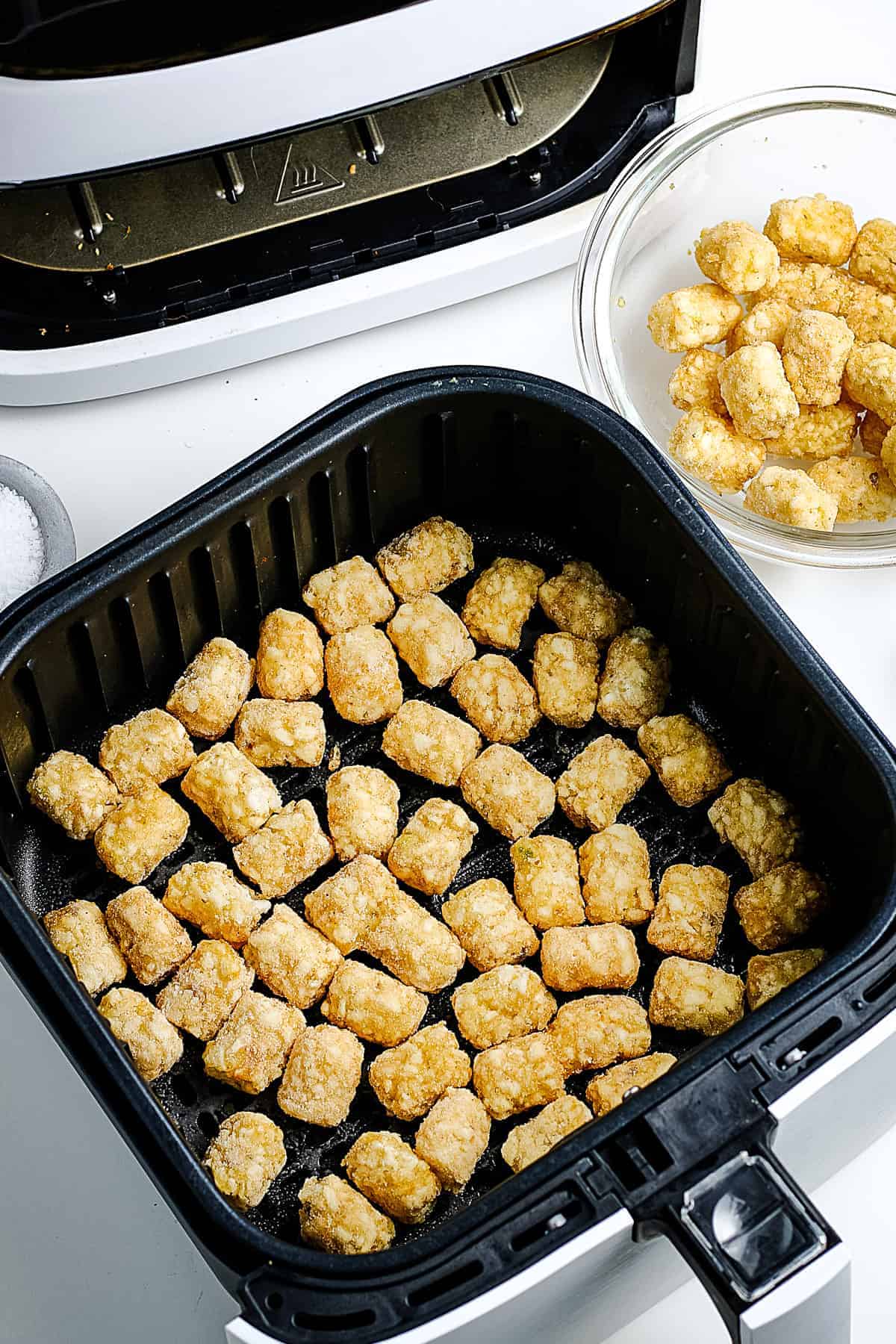 Raw Tater Tots in air fryer basket