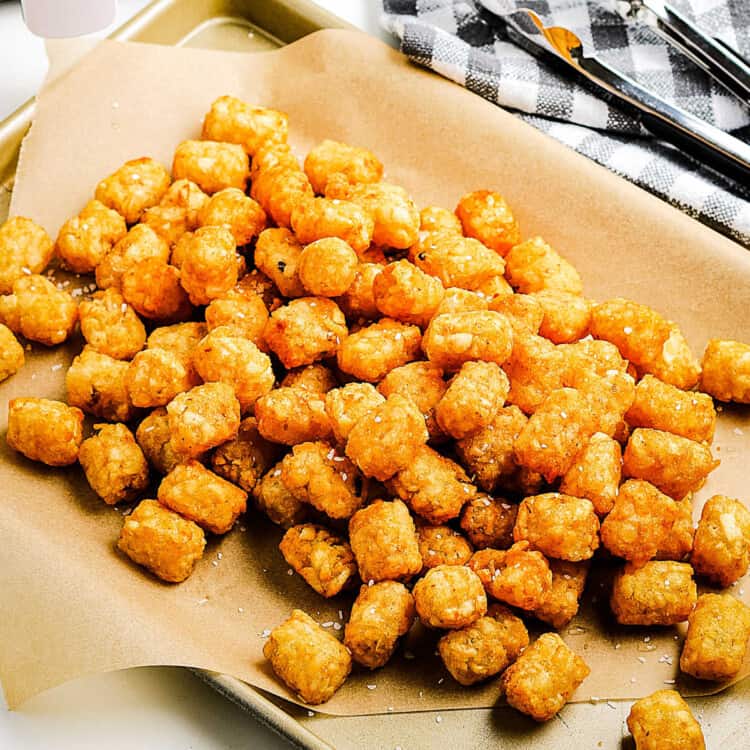 Square cropped image of Air Fryer Tater Tots on a brown piece of paper on sheet pan
