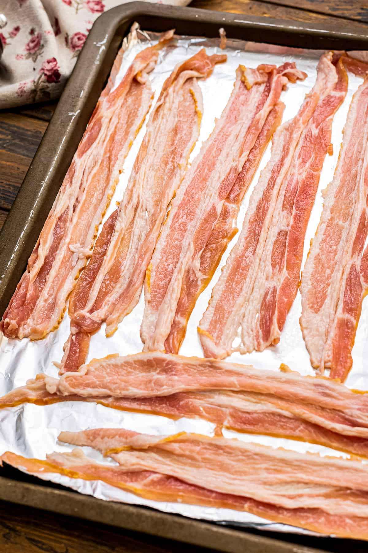 Raw Bacon Strips on a sheet pan lined with foil