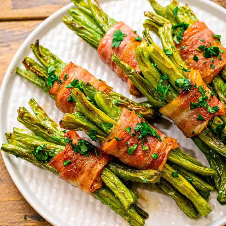 Square cropped image of bacon wrapped green beans on white plate