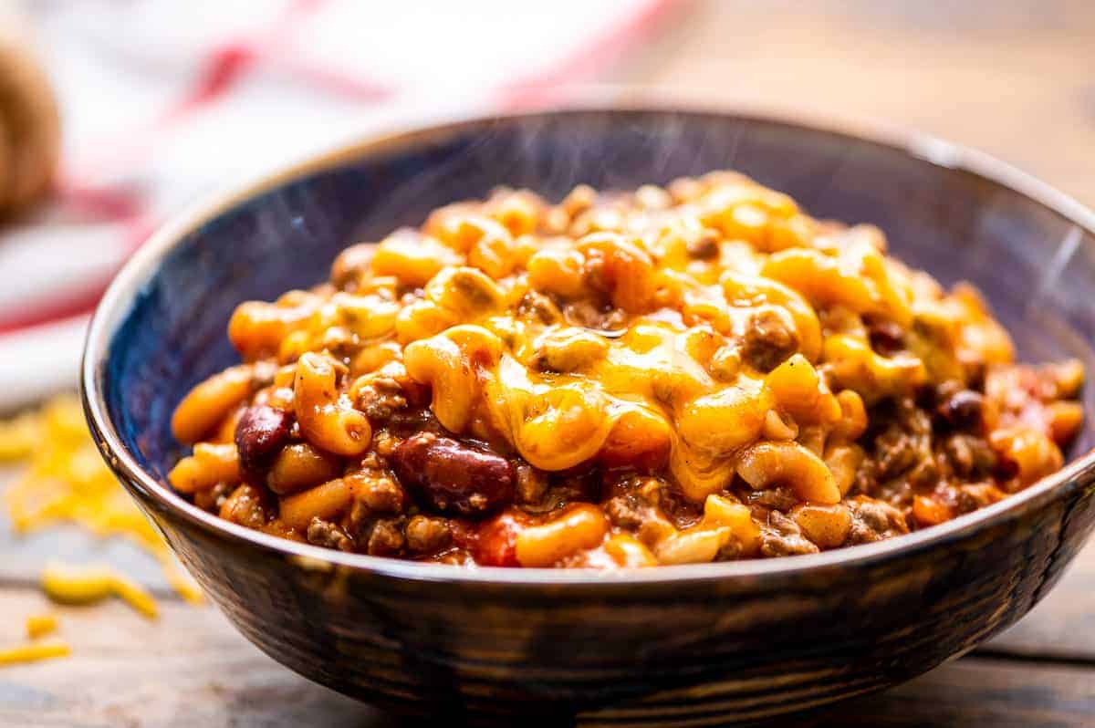 A bowl with steaming chili mac topped with cheese