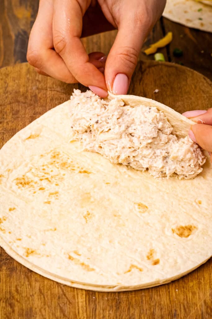 Pair of hands rolling up chicken enchilada