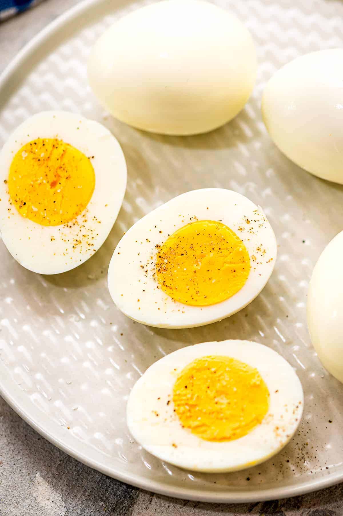 Hard Boiled Eggs cut in half sprinkled with salt and pepper on plate