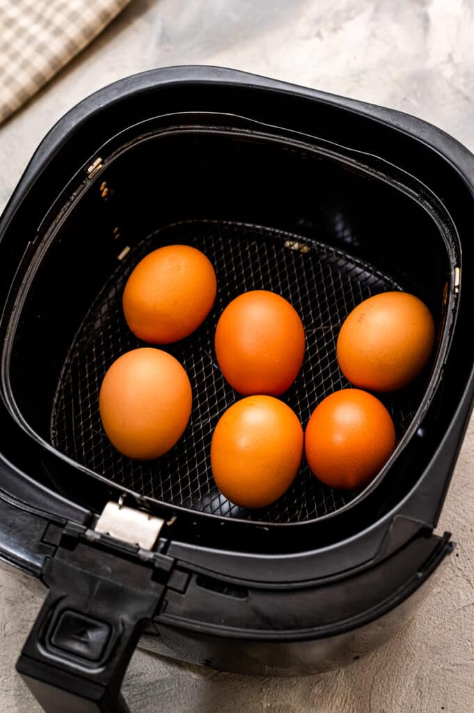 Air fryer basket with brown eggs in it