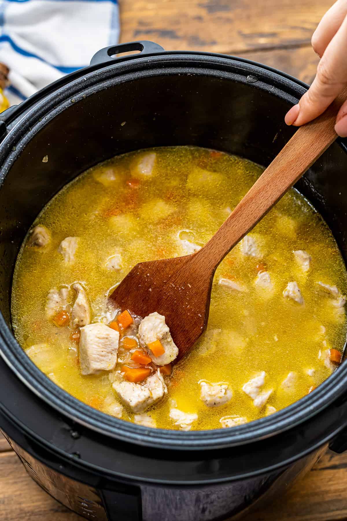 Wooden spoon stirring ingredients for chicken and rice before cooking