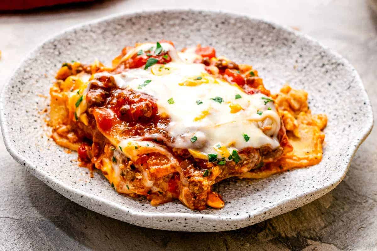 Close up image of a plate with a scoop of lasagna on it