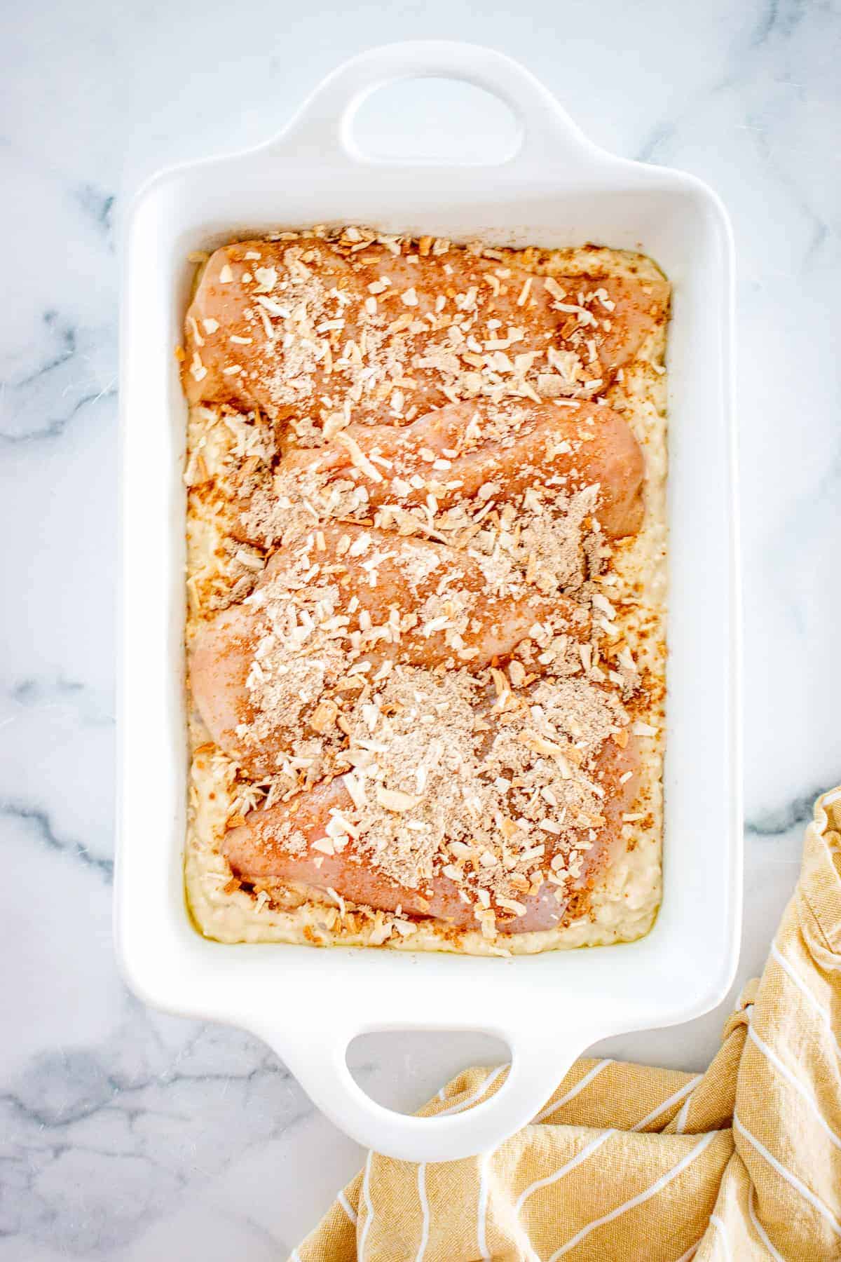 White baking dish with no peek chicken and rice sprinkled with onion soup mixture before baking