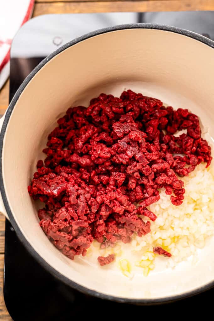 Overhead image of dutch oven with ground beef and onion before cooking