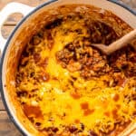 Overhead image of chili mac in dutch oven with wooden spoon