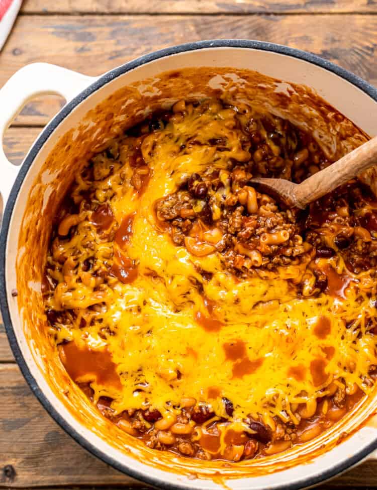Overhead image of chili mac in dutch oven with wooden spoon