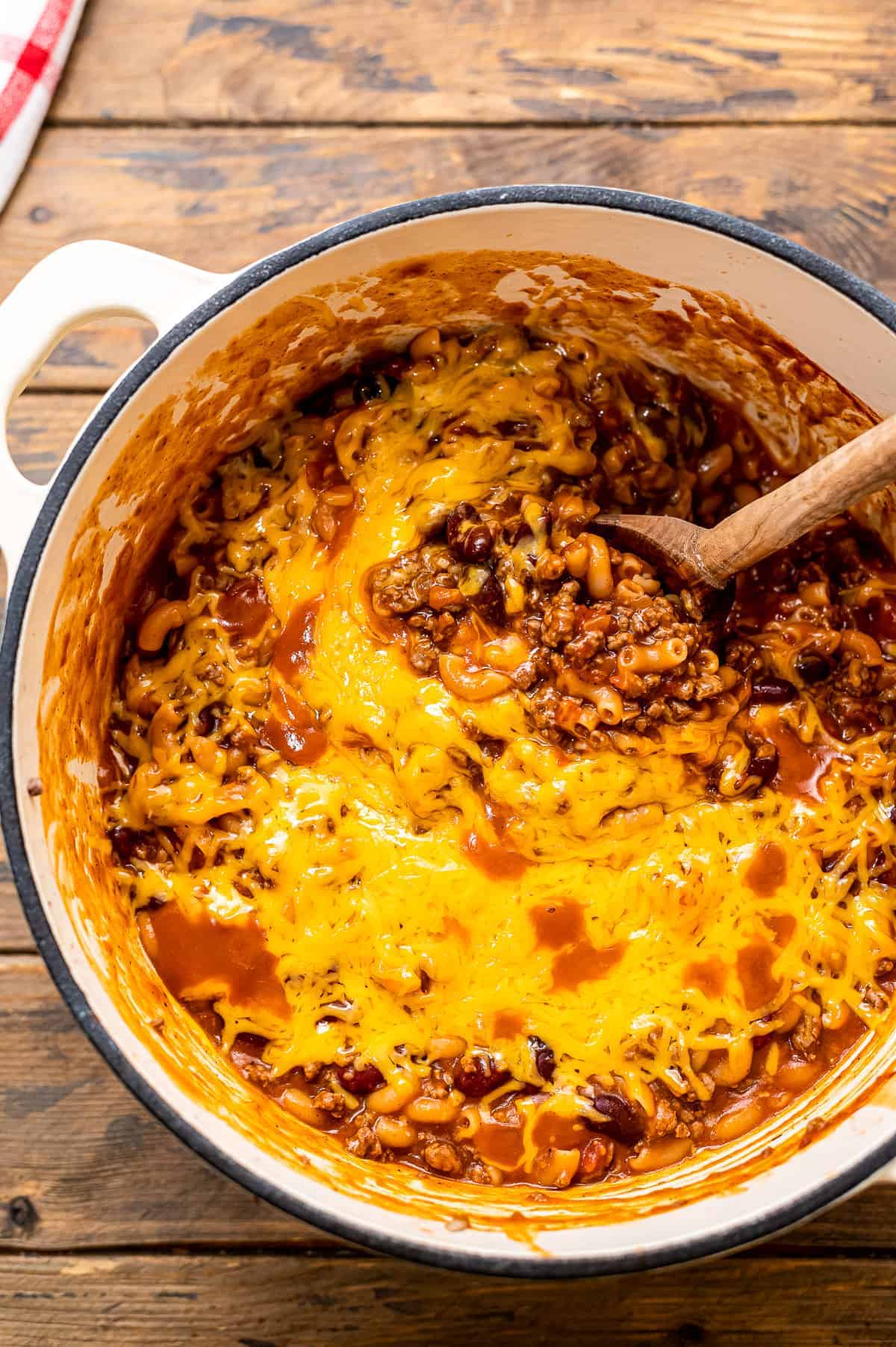 Overhead image of chili mac in dutch oven with wooden spoon