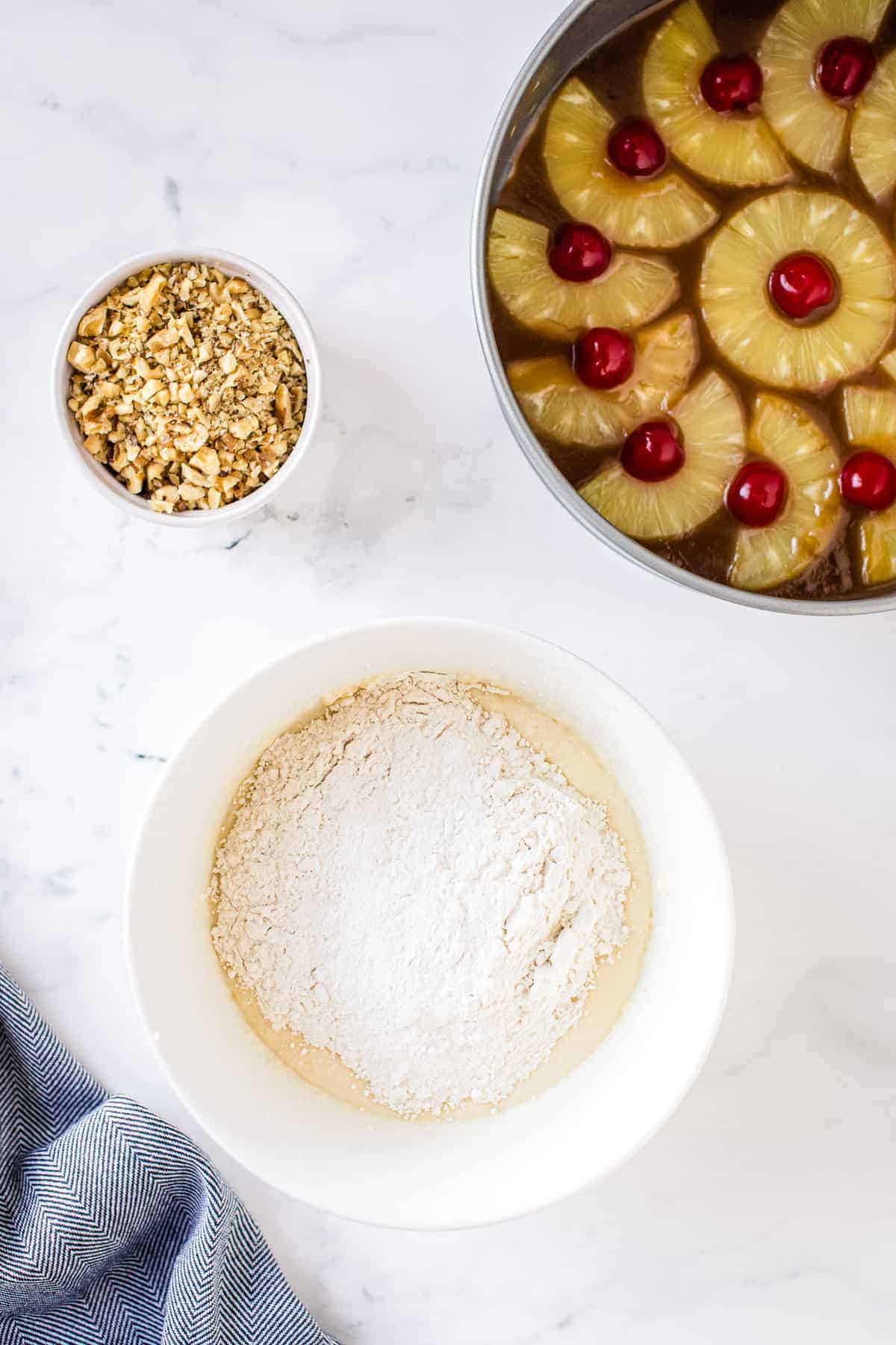 Flour on top of batter for cake in white bowl