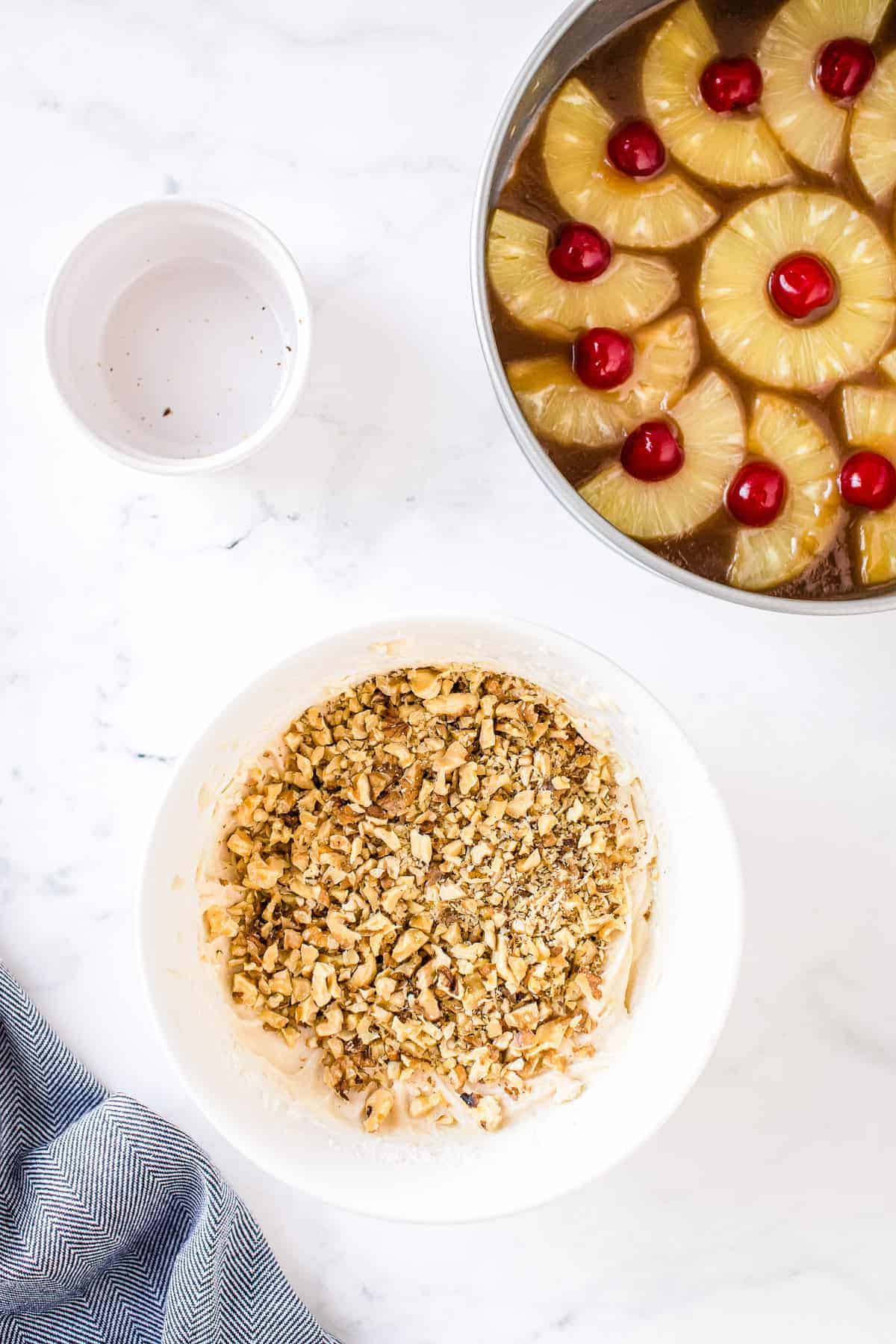 Chopped walnuts in on top of cake batter in mixing bowl before mixing